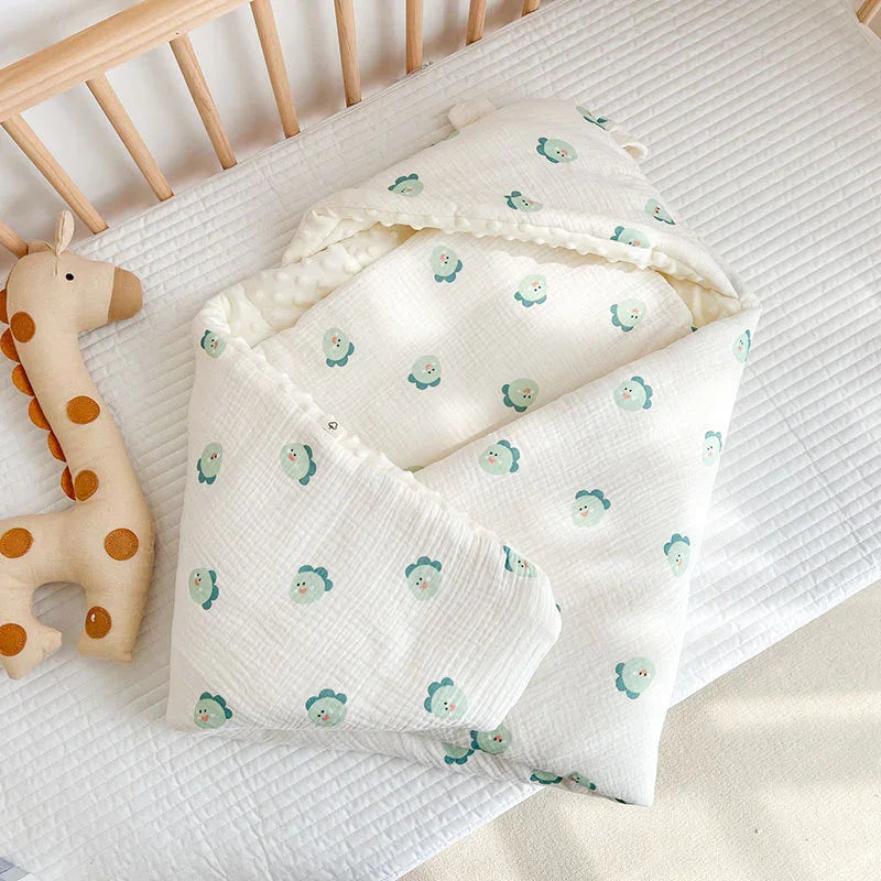 Soft white baby swaddle blanket with green flower prints inside wooden crib next to plush giraffe toy