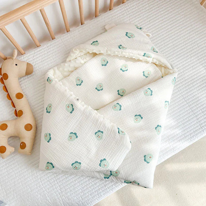 Soft white baby swaddle blanket with green flower prints inside wooden crib next to plush giraffe toy