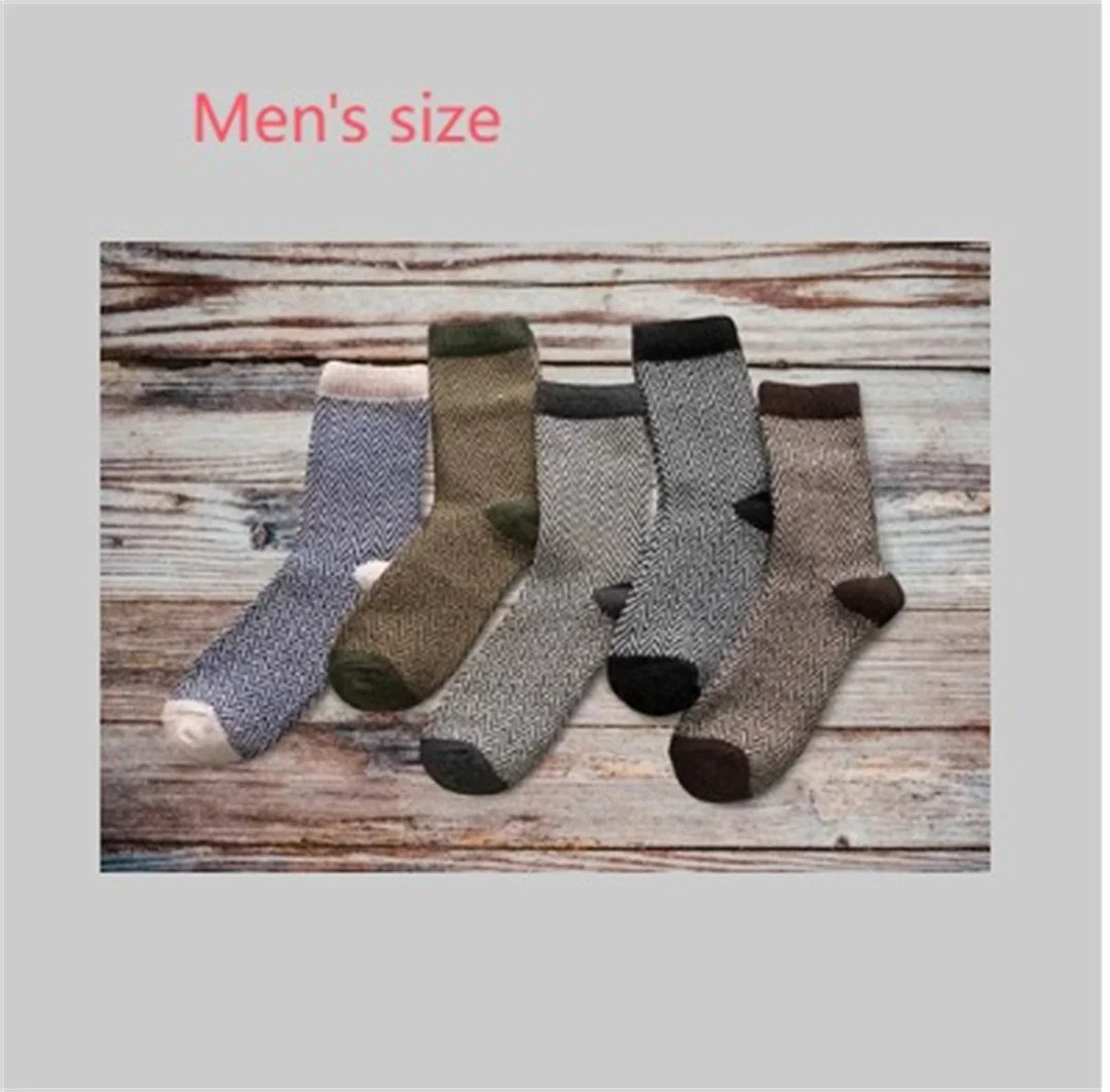 Five pairs of men's size wool blend dress socks in neutral colors laid out on wooden surface
