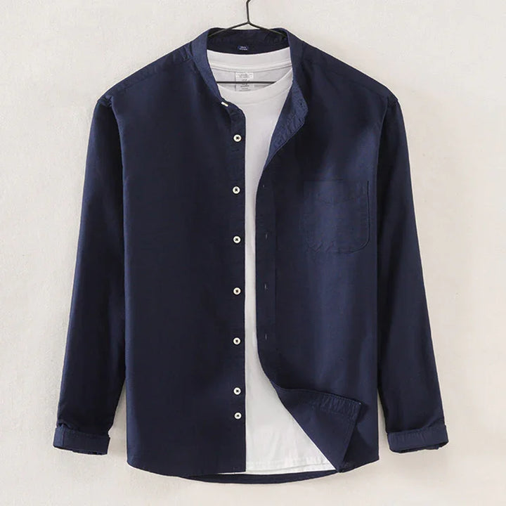 Navy blue button-up shirt over white t-shirt hanging on hanger against white wall
