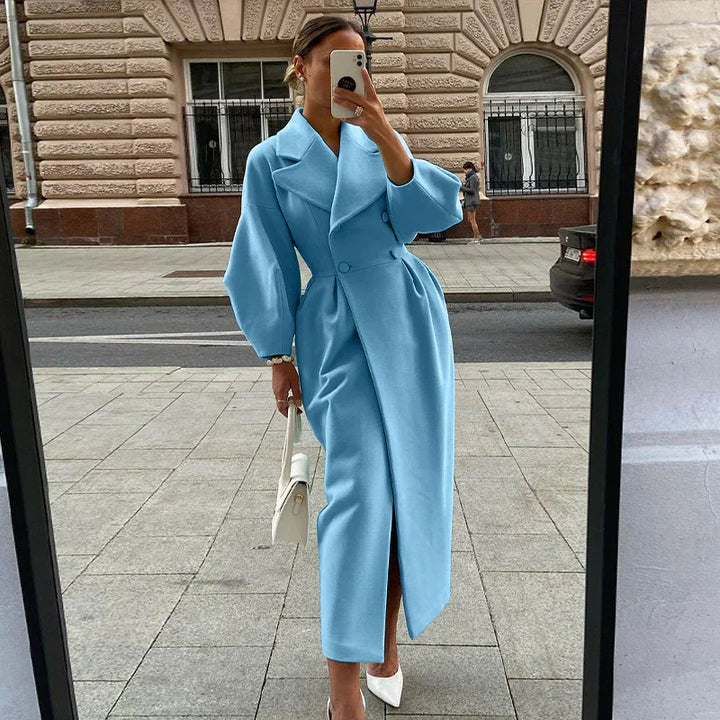 Woman taking mirror selfie wearing a stylish light blue long coat with puff sleeves and white heels on city sidewalk