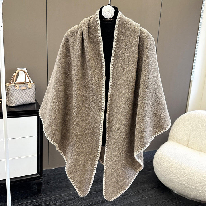 Brown wool shawl with white trim displayed on black mannequin in modern room