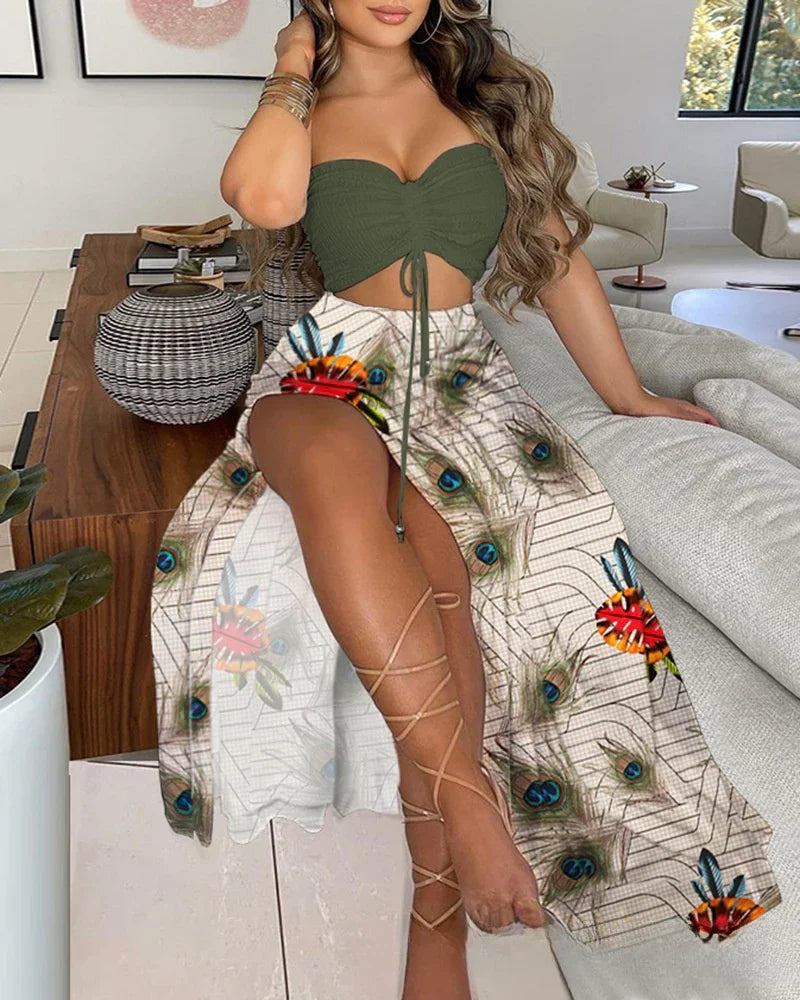 Woman sitting on sofa wearing olive green crop top and peacock feather print skirt with lace-up sandals