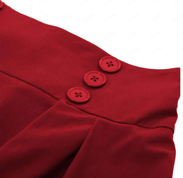 Close-up of a red garment featuring three matching red buttons and stitched pleats