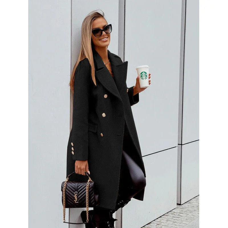 Stylish woman in black coat holding Starbucks cup and YSL handbag standing against modern wall