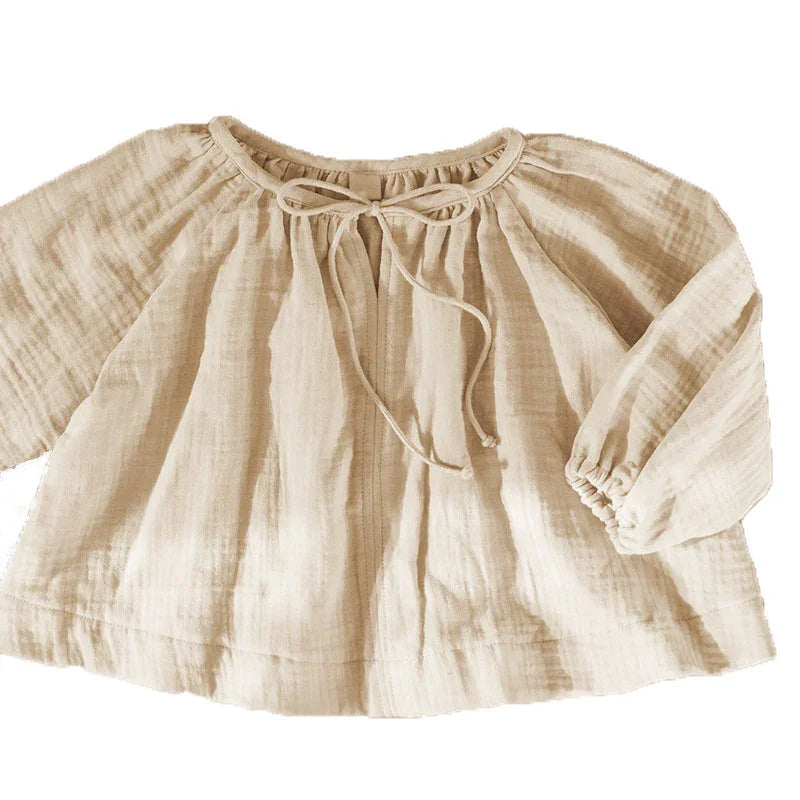 Light beige long-sleeve toddler blouse with crinkled fabric and front tie neckline