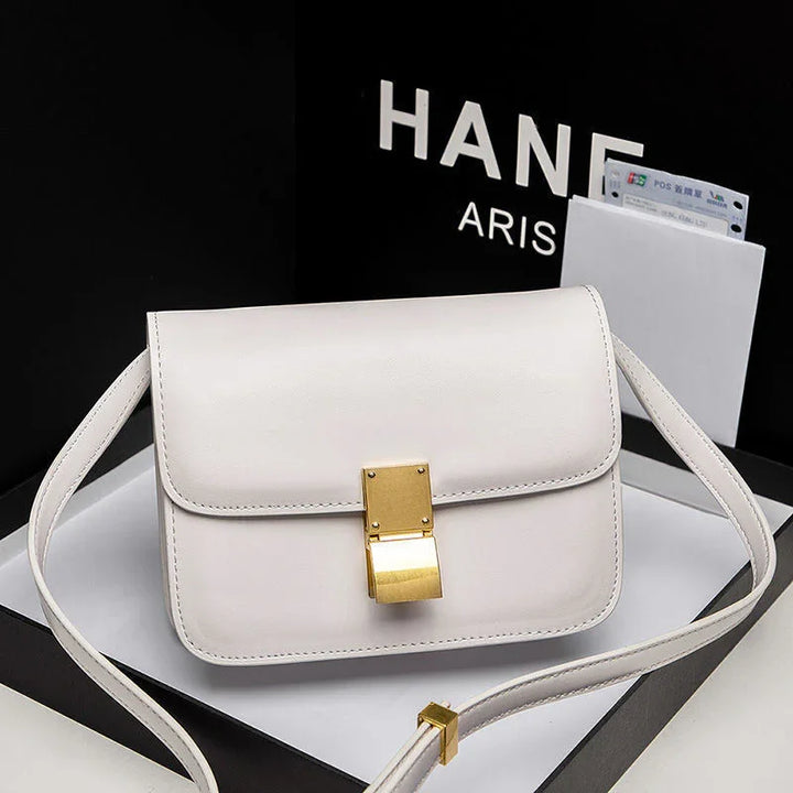 Elegant white leather shoulder bag with gold clasp and adjustable strap on black and white background