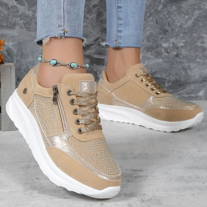 Beige women's sneakers with rhinestone embellishments and white platform soles worn with light blue frayed jeans