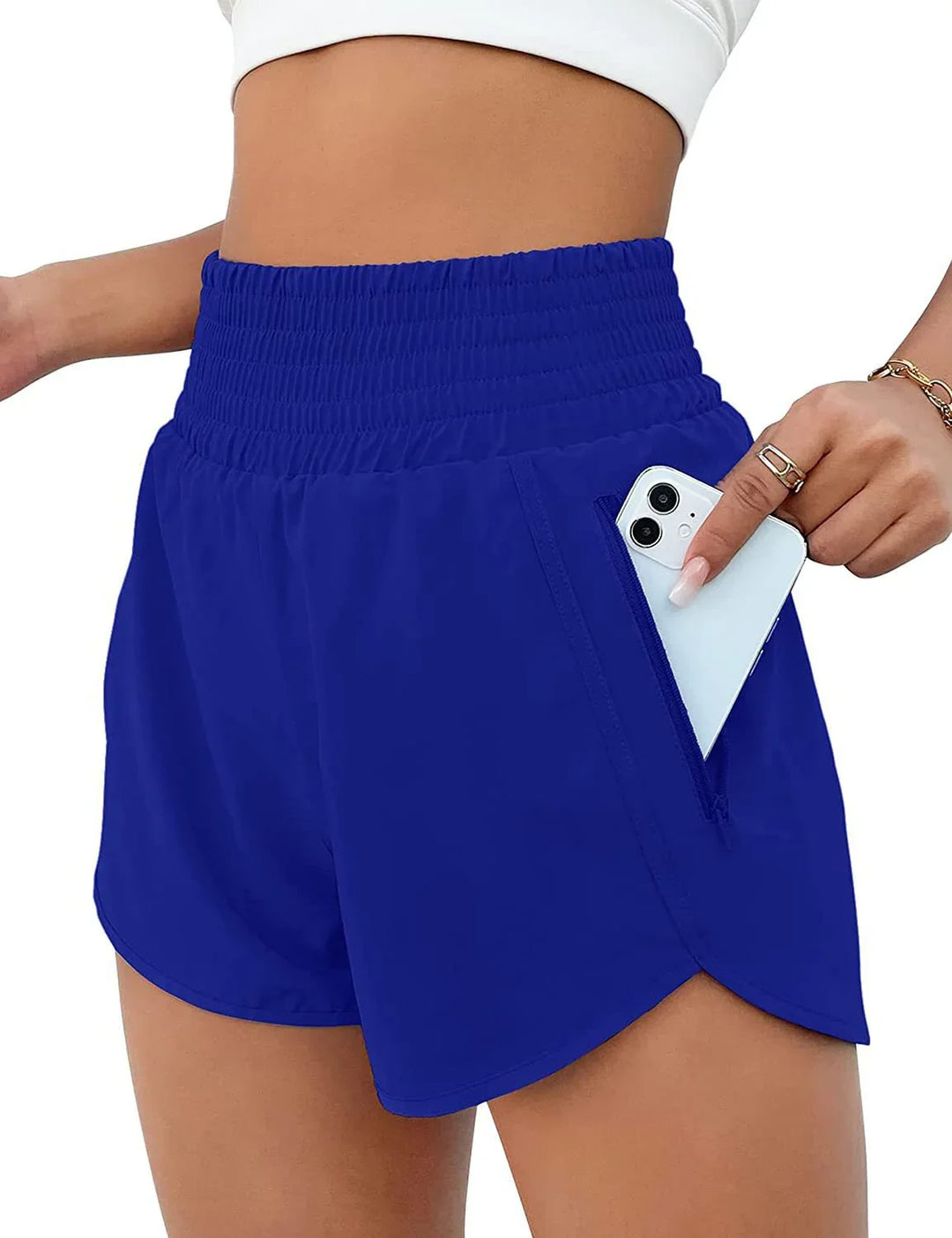 Woman wearing blue athletic shorts with high waistband and zippered pocket holding a smartphone