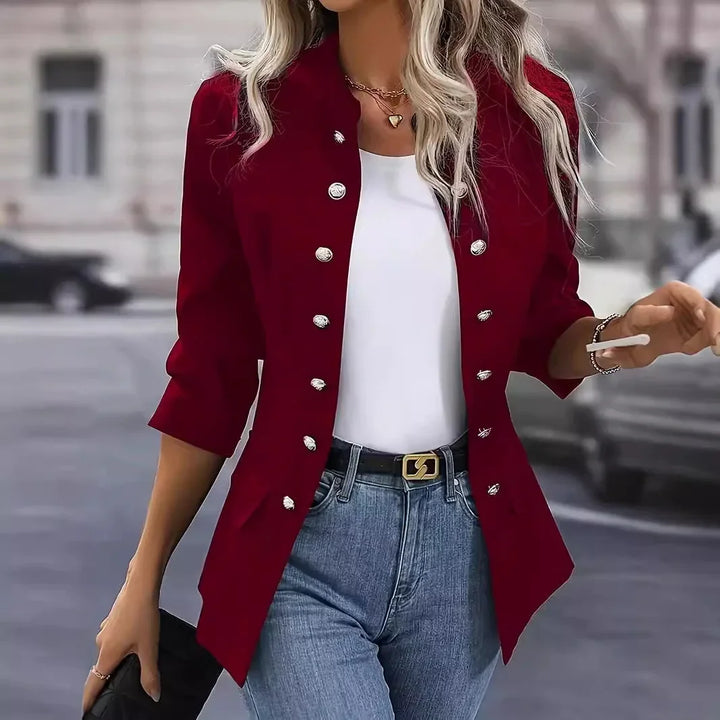 Woman wearing a stylish red buttoned blazer with white top and blue jeans, holding a black clutch