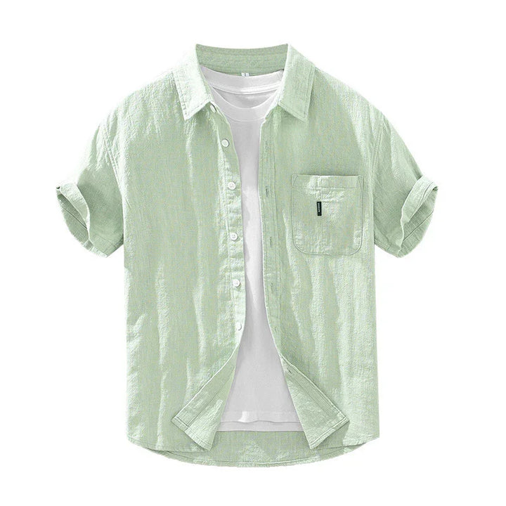 Light green short-sleeve linen shirt with rolled cuffs and front pocket over white t-shirt
