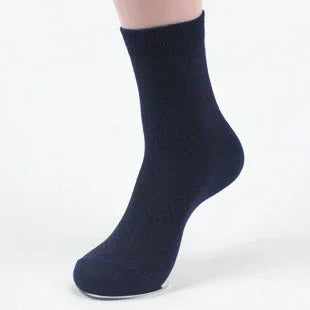 Close-up of a foot wearing a plain black ankle sock on a white background