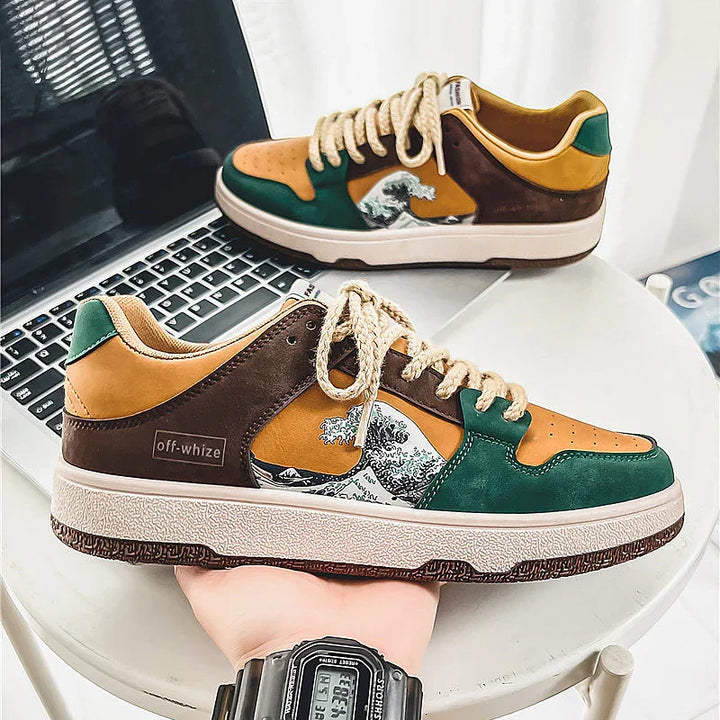 Off-whize brand sneakers with brown, green, and tan colors featuring a wave design on a table near a laptop