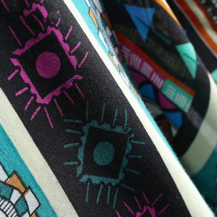 Close-up of vibrant patterned fabric with geometric shapes in teal, purple, black, and white colors