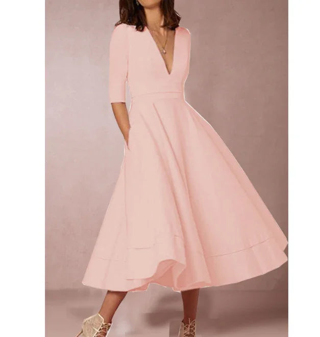 Woman wearing a blush pink midi dress with V-neck and 3/4 sleeves, paired with lace-up heels