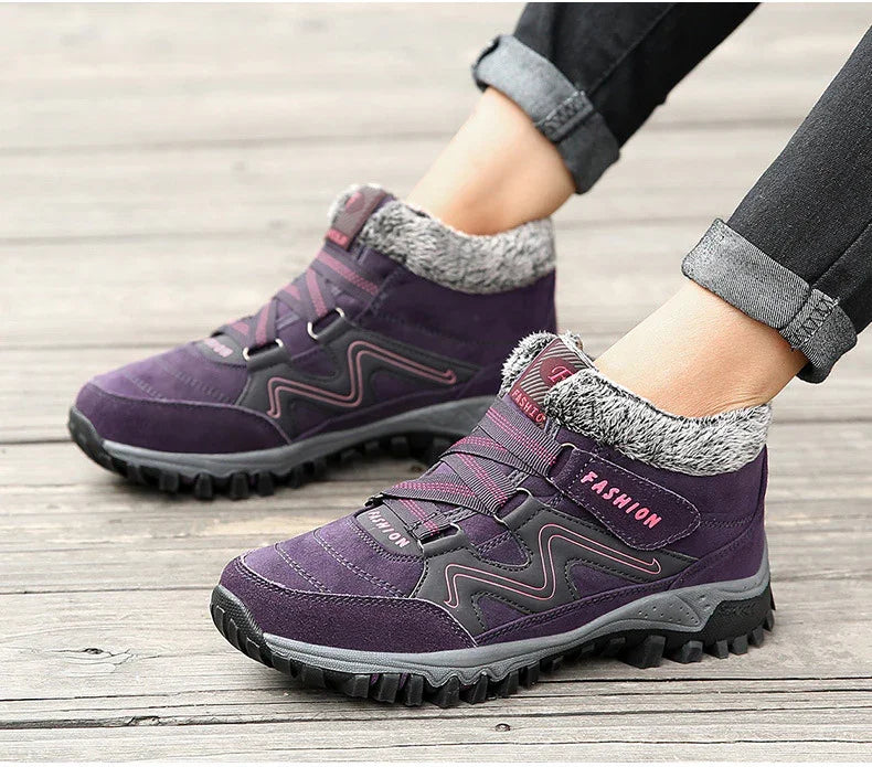 Purple winter hiking boots with faux fur collar and rugged sole worn with rolled black jeans