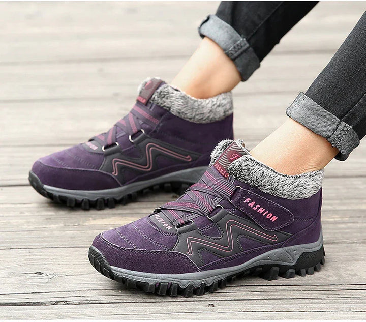 Purple winter hiking boots with faux fur collar and rugged sole worn with rolled black jeans