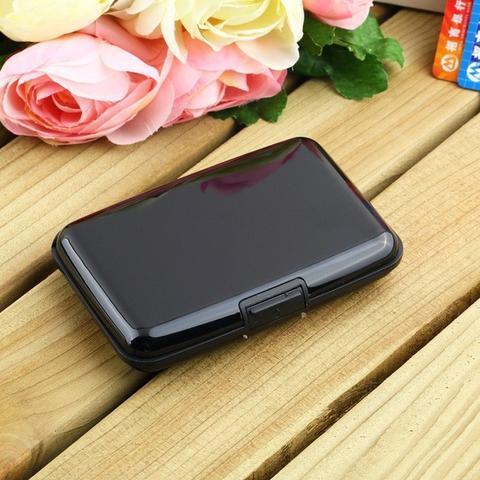 black compact card holder case on wooden surface with pink and white roses in background