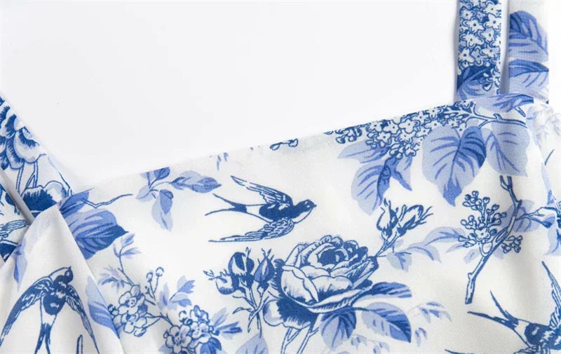 Close-up of white fabric with blue floral and bird print dress shoulder straps