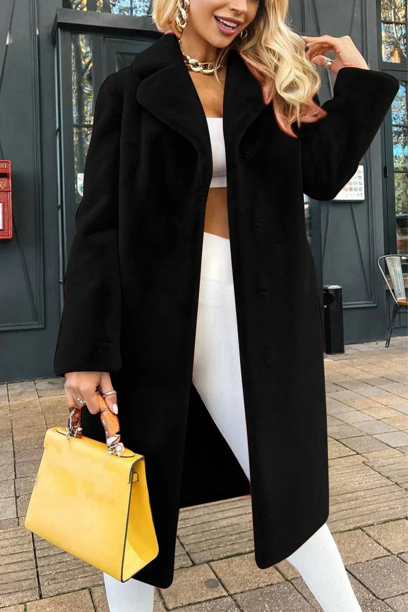 Woman wearing black coat, white crop top and pants, holding yellow handbag outdoors