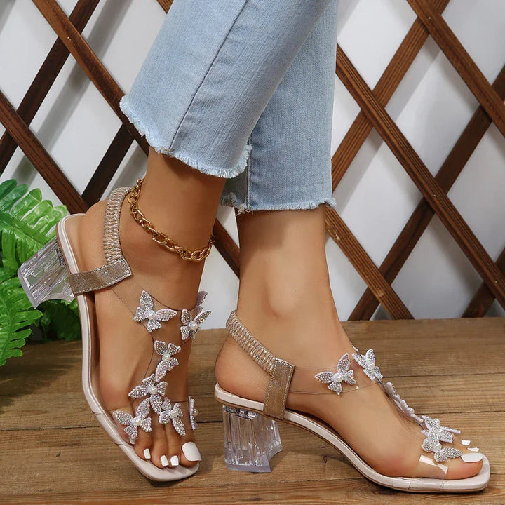 Clear heeled sandals with beaded butterfly decorations worn with light blue frayed jeans and gold anklet