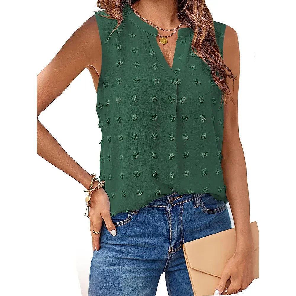 Woman wearing sleeveless green textured blouse with v-neck, paired with blue jeans and holding beige clutch