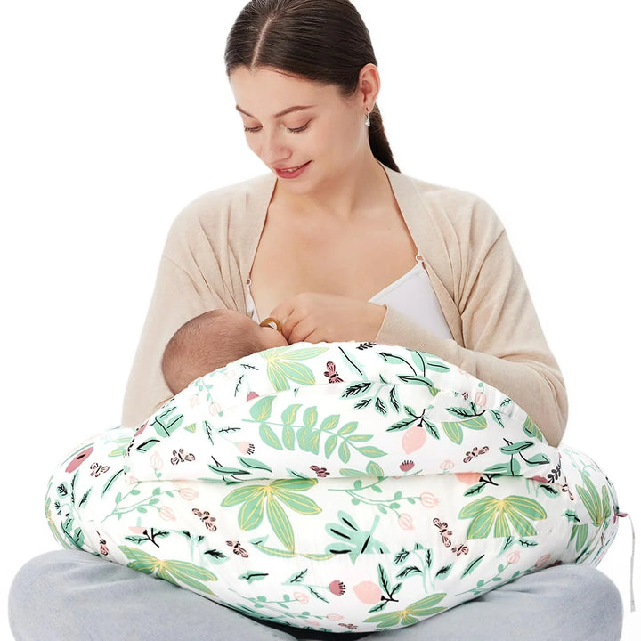 Mother breastfeeding baby using floral print nursing pillow sitting cross-legged