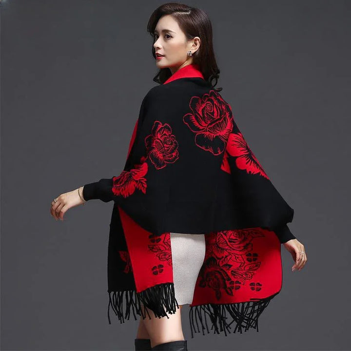 Woman wearing black and red floral shawl with fringes over white skirt against gray background