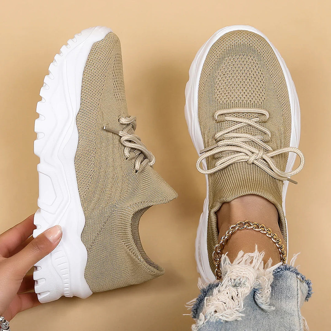 Beige knit sneakers with white chunky soles, worn with gold anklet and ripped denim jeans