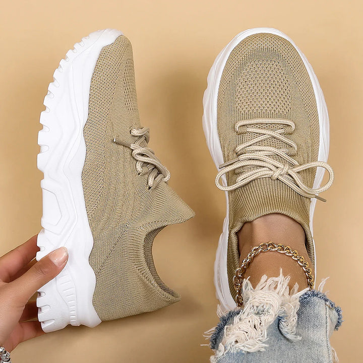 Beige knit sneakers with white chunky soles, worn with gold anklet and ripped denim jeans