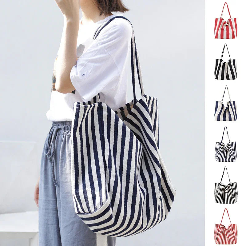 Woman wearing casual outfit carrying large navy and white striped tote bag with long handles