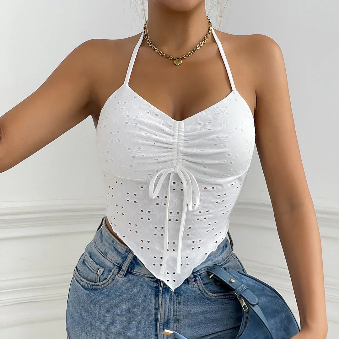Woman wearing white eyelet halter crop top with ruched front and blue jeans holding blue purse