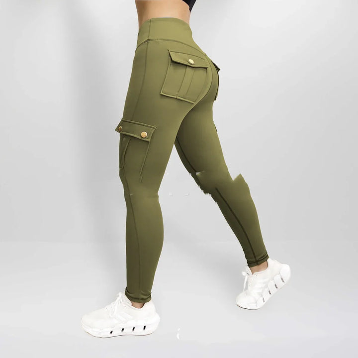 Side view of woman wearing olive green high-waisted cargo leggings with flap pockets and white sneakers