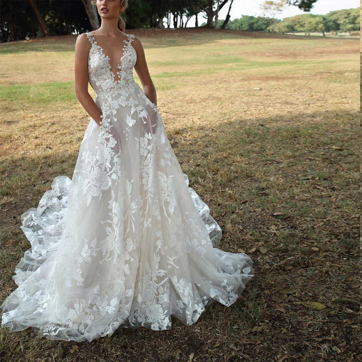 Bride wearing a floral lace wedding dress with plunging neckline standing in a grassy park