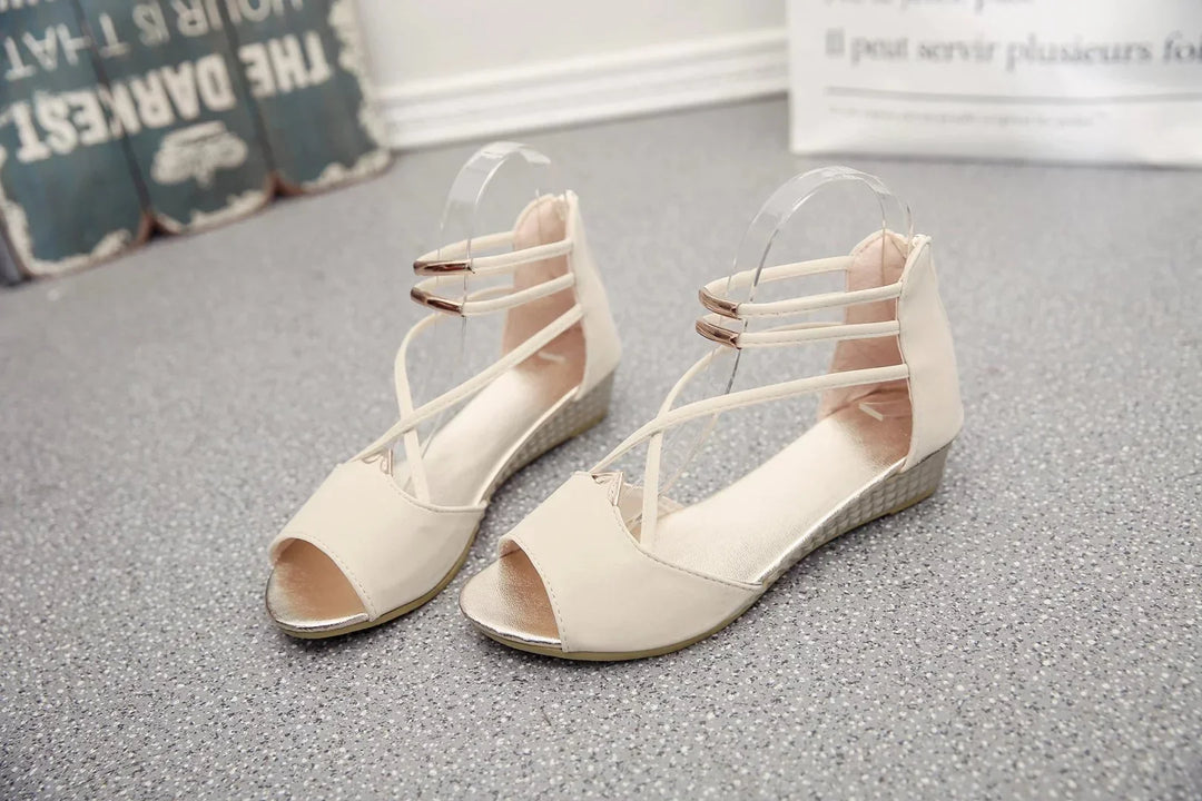 Beige open-toe wedge sandals with ankle straps and metallic accents on the heel and straps