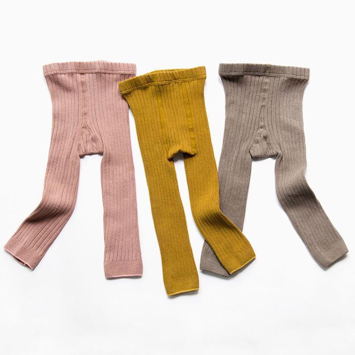 Set of three ribbed knit baby leggings in pink, mustard yellow, and gray on white background