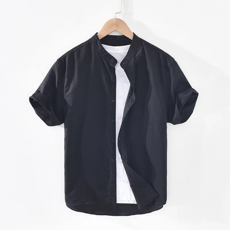 Black short-sleeve button-up shirt layered over white t-shirt on wooden hanger against white background