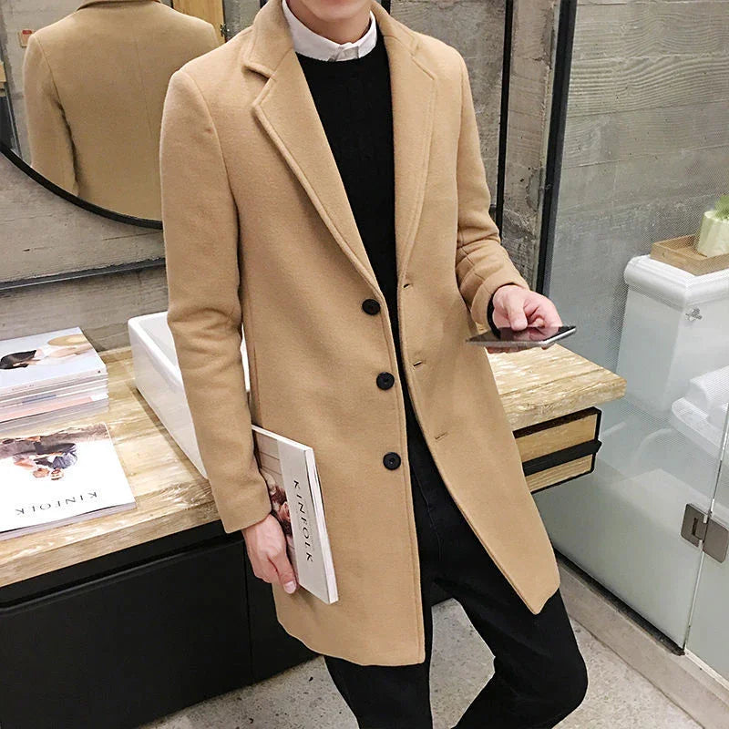 Man wearing stylish beige wool coat holding a book and smartphone in modern bathroom