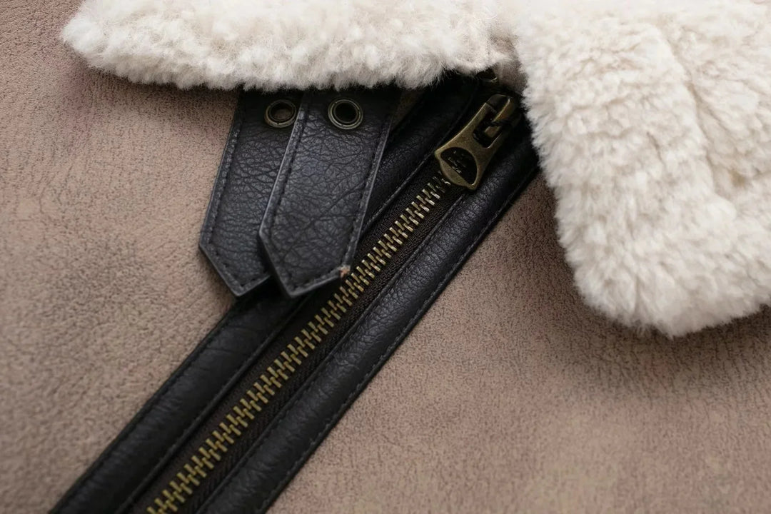 Close-up of a beige shearling jacket with black leather zipper and metal hardware