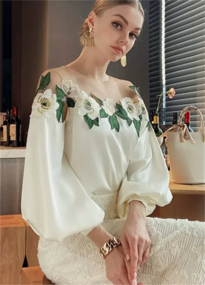 Woman wearing elegant white blouse with floral embroidery on sheer neckline and puffy sleeves