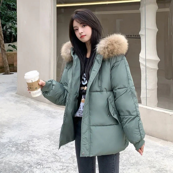 Young woman wearing green puffer jacket with fur hood holding coffee cup outdoors