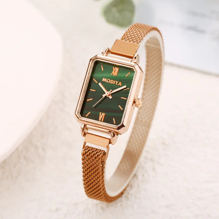 Rose gold wristwatch with rectangular green dial and mesh strap on light background