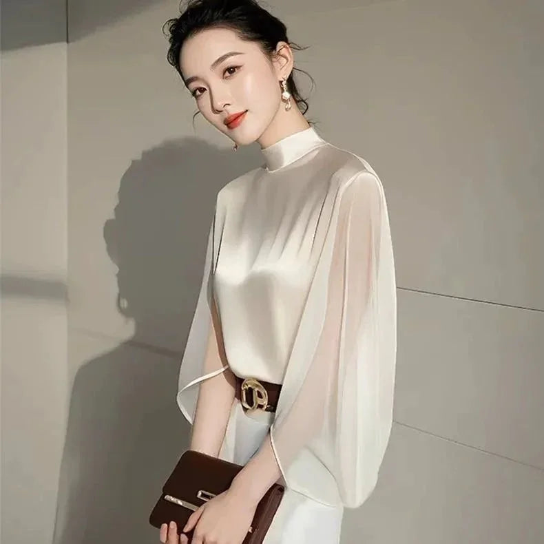 Elegant woman in a satin high-neck blouse with flowing sleeves, holding a brown clutch