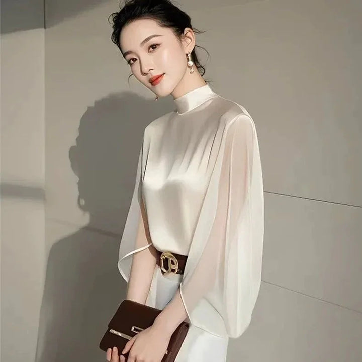 Elegant woman in a satin high-neck blouse with flowing sleeves, holding a brown clutch