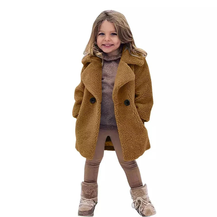 Smiling child wearing a brown teddy coat, matching leggings, and winter boots on white background