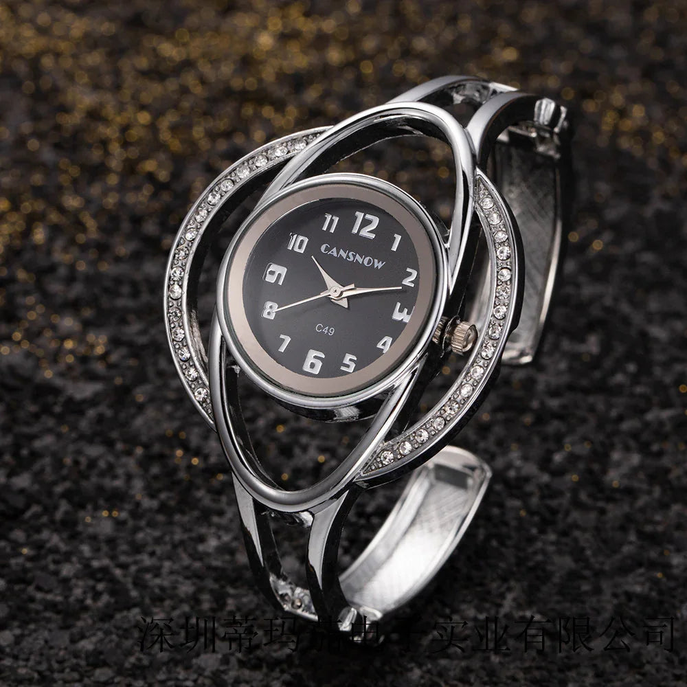 Elegant silver wristwatch with black dial and crystal-studded unique oval metal band on black glittery surface