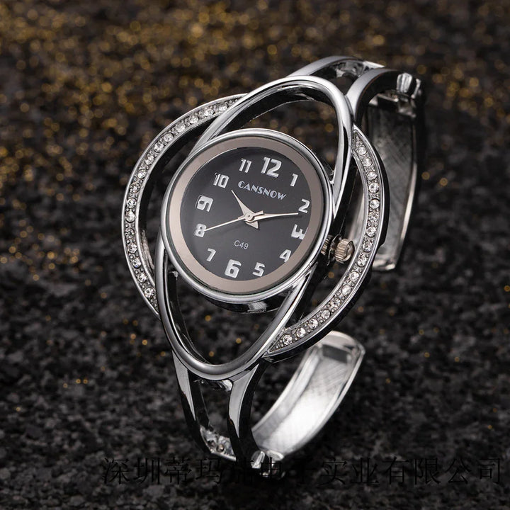 Elegant silver wristwatch with black dial and crystal-studded unique oval metal band on black glittery surface