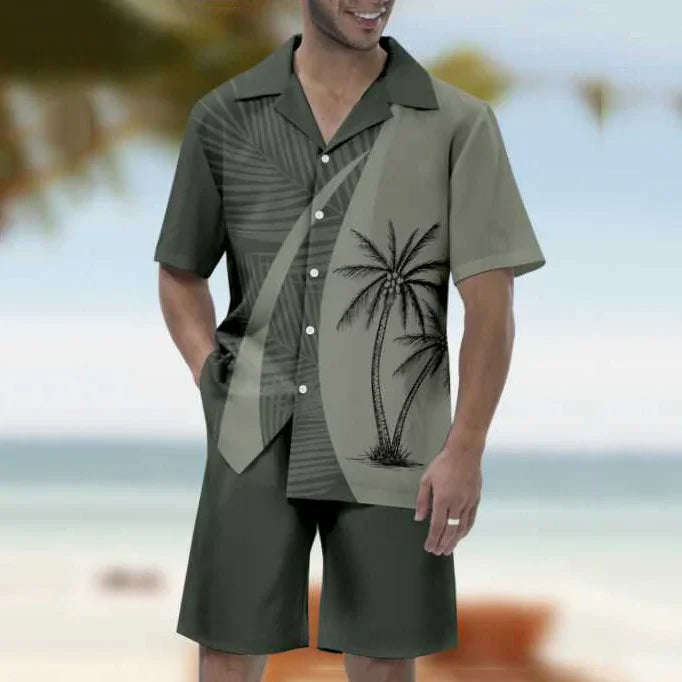 Man wearing olive green short-sleeve button-up shirt with palm tree print and matching shorts on beach
