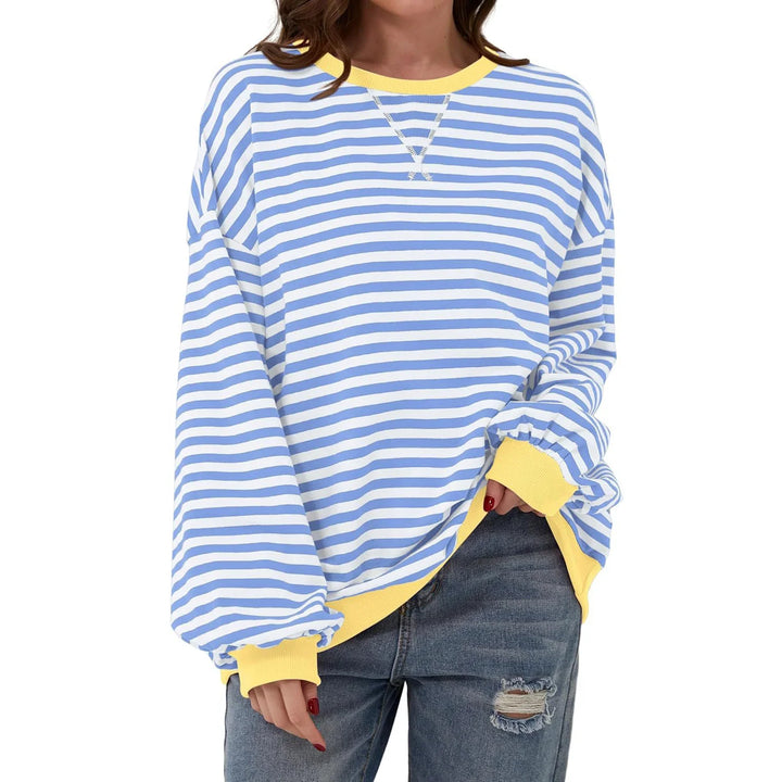 Woman wearing a blue and white striped long sleeve sweatshirt with yellow cuffs and collar, paired with ripped jeans