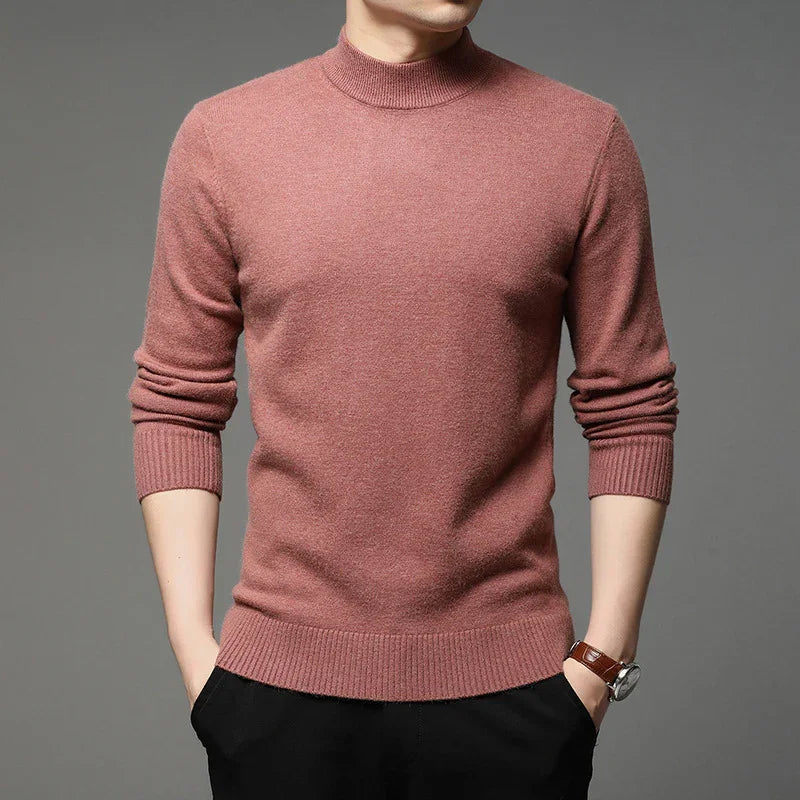Man wearing a slim fit dusty pink mock neck sweater with ribbed cuffs and hem, paired with black pants